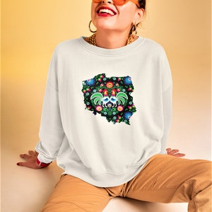 May include: White sweatshirt with a graphic of the outline of Poland with a traditional folk art design featuring roosters and flowers.