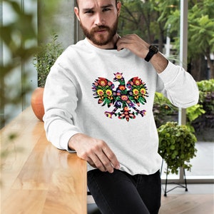 May include: White sweatshirt with a colorful floral design of the Polish national emblem, a white eagle with a crown.