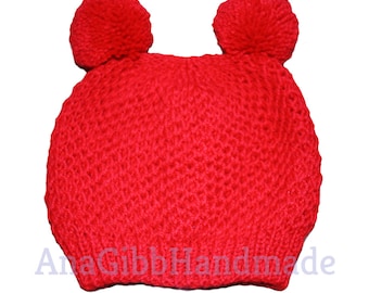 Peut inclure: Chapeau tricoté rouge avec deux pompons sur le dessus. Le chapeau est fait avec un point texturé.