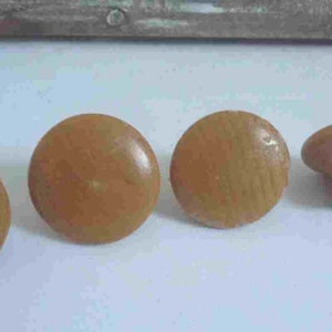 Puede incluir: Cuatro pomos de madera, tres son redondos y uno es redondo con un tallo. Los pomos son de color marrón claro.