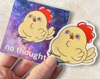 May include: Two stickers featuring a cartoon chicken with a red comb and a yellow body. One sticker is on a background with a galaxy design and the words "no thought". The other sticker is a die-cut of the chicken.