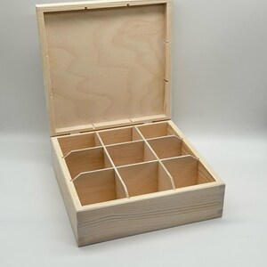 May include: A wooden box with a hinged lid and eight compartments. The box is made of light wood and has a natural finish. The lid is open and the compartments are visible.