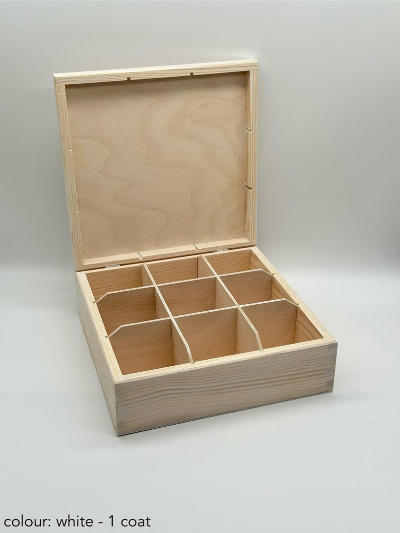 May include: A wooden box with a hinged lid and eight compartments. The box is made of light wood and has a natural finish. The lid is open and the compartments are visible.