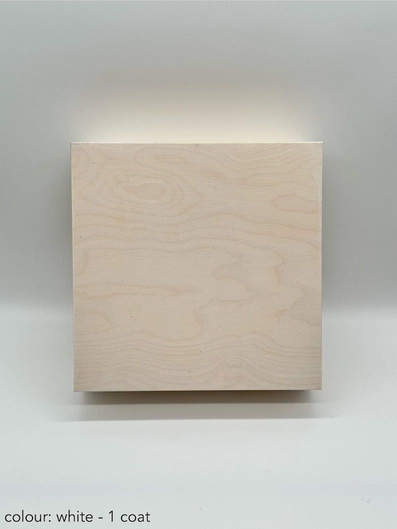 May include: A square piece of wood painted white. The wood has a natural grain pattern. The paint is a solid white colour with one coat of paint.