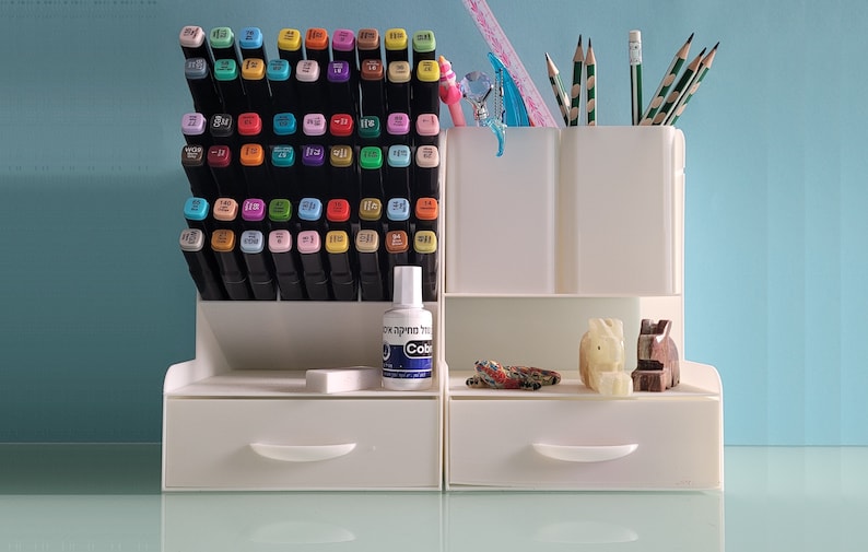 May include: White plastic organizer with two drawers, a top shelf for pens and pencils, and a bottom shelf for markers. The organizer is filled with colorful markers, pencils, and a bottle of white liquid labeled "Colorless Blending Solution".