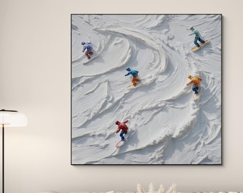 May include: A framed art print depicts five snowboarders carving down a textured, white snow-covered slope. The snowboarders wear colorful outfits, including red, blue, and yellow. The artwork is displayed above a light-colored sofa in a living room setting.