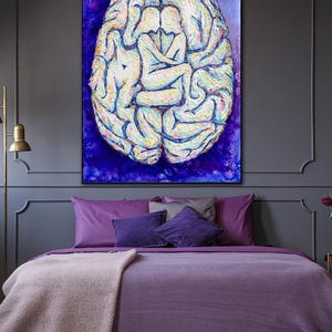 May include: An abstract painting depicting a brain shape with figures embracing within, set against a dark blue backdrop. The artwork hangs above a bed with purple bedding and cushions, creating a harmonious colour scheme.