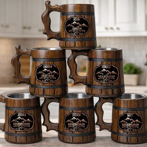 Pode incluir: Uma pilha de seis canecas de cerveja de madeira com interiores em aço inoxidável. Cada caneca tem um acabamento em madeira escura, uma alça grande e um rótulo decorativo com um nome e um título como "Groom" ou "Best Man". Os rótulos também incluem uma data.