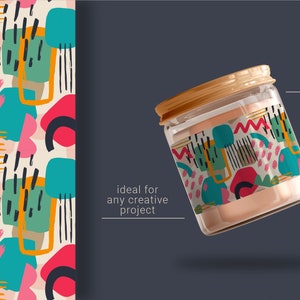 May include: A glass jar with a gold lid is decorated with a colorful abstract pattern. The pattern features geometric shapes, lines, and dots in shades of pink, blue, green, yellow, and black. The jar is floating against a dark gray background.