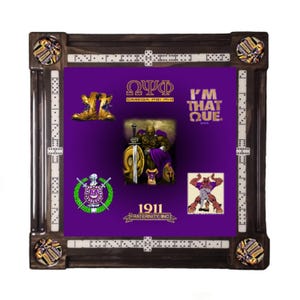 May include: A decorative dominoes set with a dark wood frame and a purple centre. The centre features graphics and text related to Omega Psi Phi Fraternity, Inc. The set includes dominoes and decorative corner pieces.