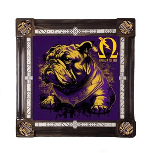 May include: A square domino set featuring a purple and gold bulldog graphic with the text "OMEGA PSI PHI". The set has a dark wood frame with dominoes and decorative corner pieces.