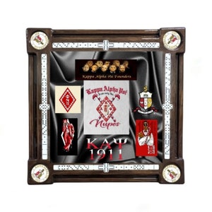 May include: A wooden domino table with a black felt surface and white dominoes. The table features a red and white Kappa Alpha Psi fraternity logo, a red and white "Kappa Alpha Psi Founders" banner, and a red and white "Kappa Alpha Psi Fraternity Inc." logo. The table also features a red and white "1911" logo.