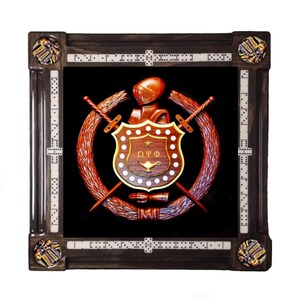 May include: A framed domino set with a central emblem of a shield, swords, and a helmet, set against a black background. The frame is dark brown with dominoes embedded in the corners and sides. The emblem is surrounded by a wreath.