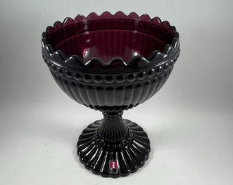 May include: A black glass bowl with a scalloped rim and a pedestal base. The bowl has a deep purple hue and a textured surface.