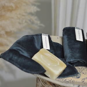 Peut inclure: Quatre linges en velours bleu fonc&eacute; pli&eacute;s et empil&eacute;s dans un bol &agrave; motifs blancs et bleus. Une barre de savon repose sur les linges. Les linges portent une &eacute;tiquette blanche avec le texte "The Conscious Cloth" imprim&eacute; dessus.