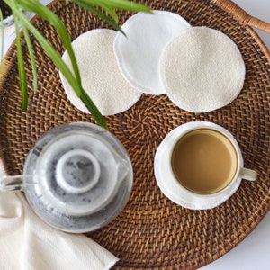 Può includere: Un vassoio in vimini con una tazza di caffè, una teiera di vetro e quattro dischetti di cotone bianchi.