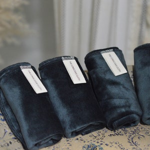Peut inclure: Cinq lingettes r&eacute;utilisables pour le d&eacute;maquillage de couleur vert fonc&eacute; avec des &eacute;tiquettes blanches indiquant "The Conscious Cloth".