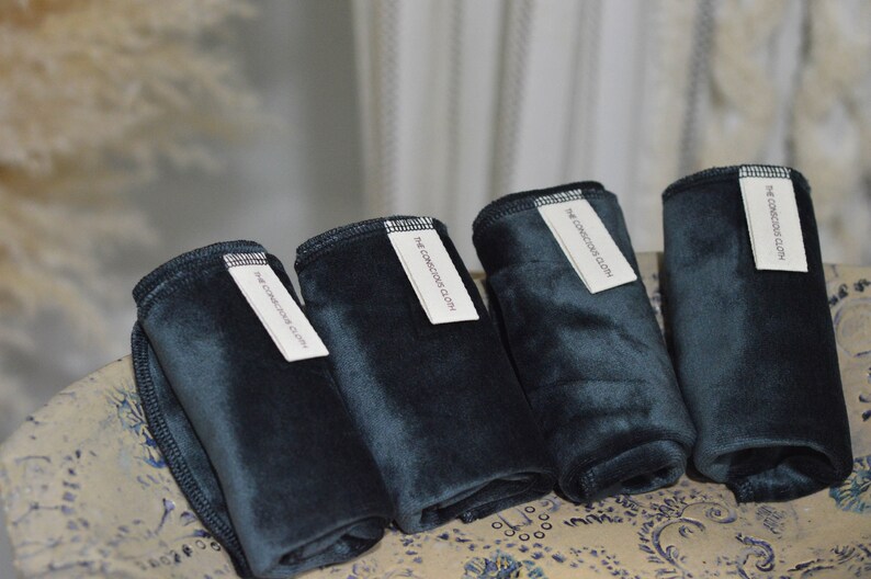Peut inclure: Cinq lingettes r&eacute;utilisables pour le d&eacute;maquillage de couleur vert fonc&eacute; avec des &eacute;tiquettes blanches indiquant "The Conscious Cloth".