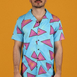 May include: A light blue short-sleeved button-down shirt with a geometric pattern of pink and purple triangles.