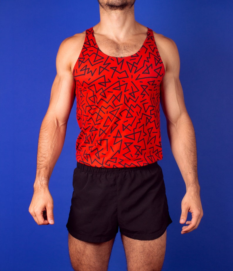 以下が含まれることがあります： 黒の幾何学模様がついた赤いタンクトップと黒いアスレチックショーツ