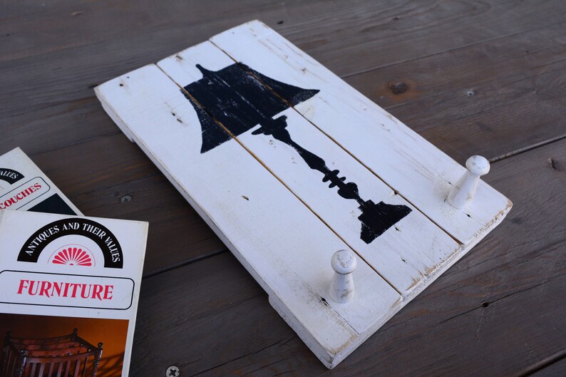 May include: White wooden wall decor with a black silhouette of a lamp and two white wooden hooks.