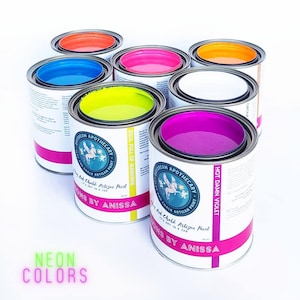 May include: Eight paint cans with neon colors, including hot pink, bright yellow, orange, and blue. The cans are labeled "Dream Apothecary" and "Moons by Anissa".
