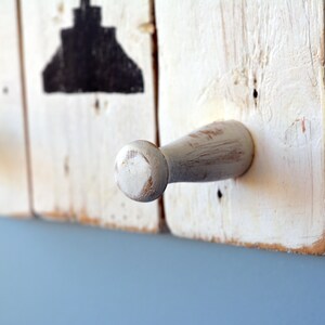 May include: White wooden coat rack with two white wooden hooks. The rack is distressed and has a rustic look.