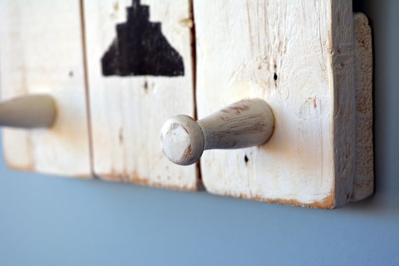 May include: White wooden coat rack with two white wooden hooks. The rack is distressed and has a rustic look.