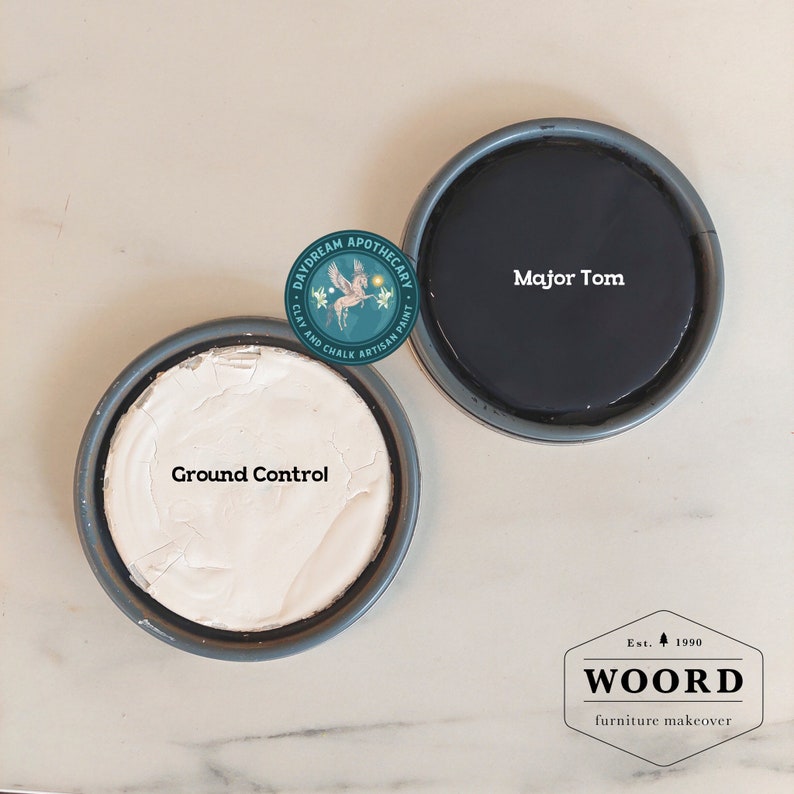 May include: Two paint tins, one white and one black. The white tin says "Ground Control" and the black tin says "Major Tom". The tins are labelled with the Daydream Apothecary logo and the text "Clay and Chalk Artisan Paint".