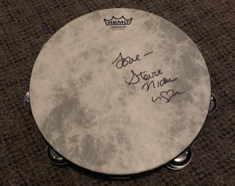 May include: A white Remo Fiberglass tambourine with black jingles and a black rim. The tambourine is signed "Joe - Steve Nick with a heart".