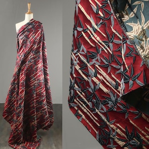 May include: A bolt of red fabric with a bamboo leaf pattern. The fabric is draped over a mannequin, showcasing the design. The bamboo leaves are in shades of gray, black, and beige, creating a striking contrast against the red background.