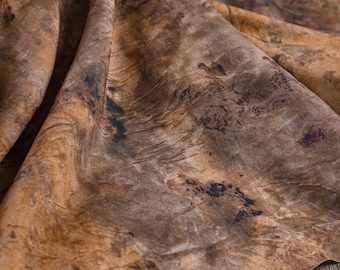 May include: Close-up of a fabric with a marbled pattern in shades of brown, tan, and black. The fabric has a textured appearance with visible folds and variations in color, creating a natural, organic aesthetic.
