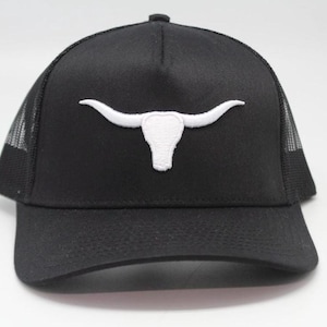 May include: Black trucker hat with a white embroidered longhorn skull design. The hat features a mesh back and a curved brim. A classic accessory for casual wear, this hat is suitable for outdoor activities.
