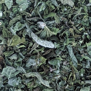 May include: Close-up of dried green herbs, likely mint, with a slightly frosty appearance.