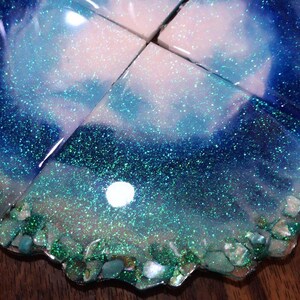 May include: Set of four blue and green glitter resin coasters with a white swirl design and iridescent shell accents.