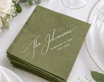 May include: A stack of square olive green paper napkins featuring white printed text. The text reads The Johnsons in a cursive script, followed by the date 14 February 2026, and the location New York in a clean, sans-serif capital font.