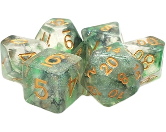 May include: A set of polyhedral dice featuring a translucent green and clear resin base with embedded silver glitter and dark inclusions. Each die has engraved numbers filled with gold paint, including a twenty-sided die showing the number twenty.