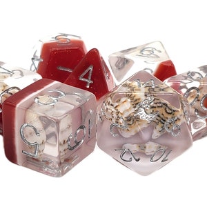May include: Set of six clear dice with red and white accents. The dice have silver numbers and contain seashells inside.