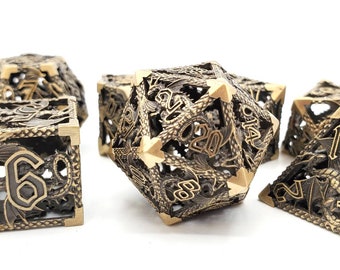 May include: Set of seven gold metal dice with a dragon design. The dice are hollow and have a detailed dragon pattern with gold numbers.