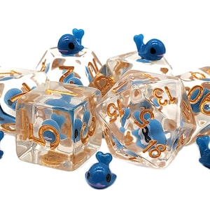 May include: A set of six clear dice with gold numbers and blue whale charms. The dice are translucent and show the numbers 1, 2, 3, 4, 5, and 6.