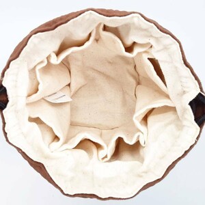 May include: A brown drawstring bag with a white cotton lining. The bag has a drawstring closure and is made of a soft, durable fabric.