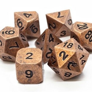 May include: A set of seven copper-colored metal dice with black numbers. The dice are in various shapes and sizes, including a d20, d12, d10, d8, d6, and d4.