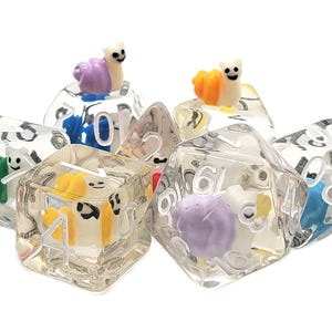 May include: A set of six clear dice with different colored snail charms. The dice are numbered 1 through 6 and the snails are purple, yellow, and green.