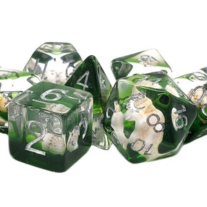 May include: Set of seven green and clear dice with silver numbers and white seashells embedded inside. The dice are for role-playing games.
