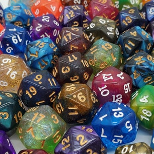 May include: A collection of colorful, glittery, and iridescent dice with various numbers on each face. The dice are made of a translucent material and have a speckled appearance.
