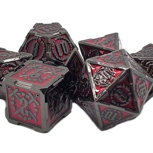 May include: Set of seven black and red metal dice with intricate designs. The dice are polyhedral and feature a variety of numbers and symbols.