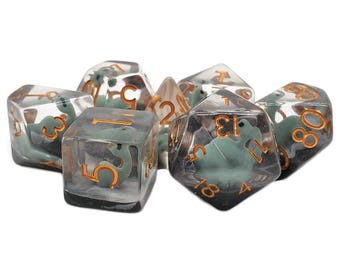 May include: A set of six clear dice with green dinosaur figures inside. The dice are numbered 1 through 6 and have gold numbers.