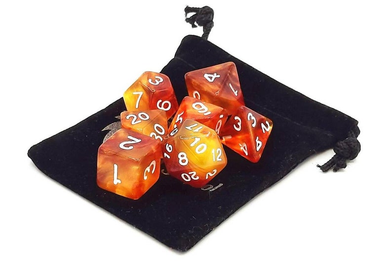 May include: A set of seven polyhedral dice in a black velvet bag. The dice are translucent and have a red and yellow swirl pattern. The numbers on the dice are white.