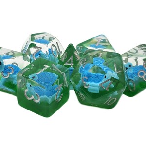 May include: A set of six clear green and blue dice with a turtle design. The dice are numbered 1 through 6.