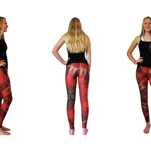 Pode incluir: Três modelos vestindo tops de tanque pretos e leggings com padrão vermelho, verde e amarelo. As leggings têm um design floral.